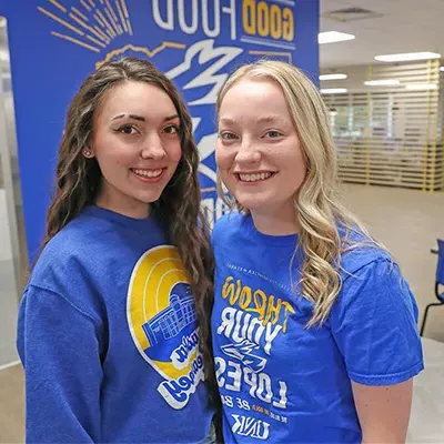 two young women pose for a photo in the dining hall